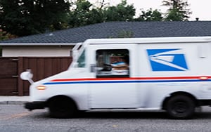 postal truck driving past house